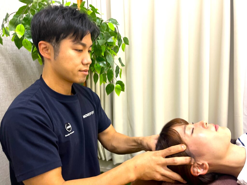 仰向けの状態で首まわりに手を当て、呼吸が深く入るように整えている様子